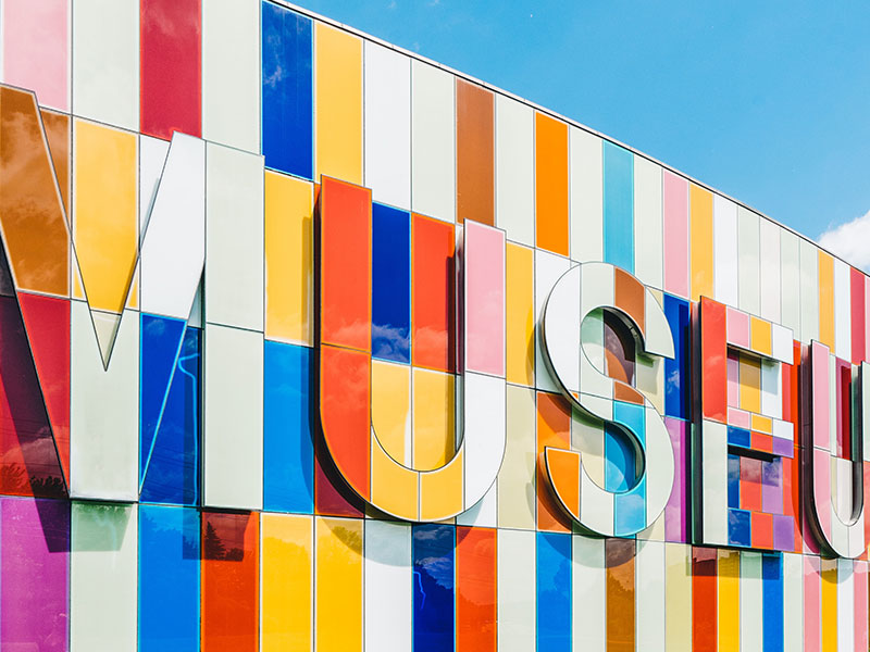 Colorful striped museum facade with large letters.