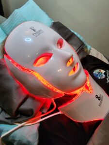 LED light therapy mask glowing in red on a surface.