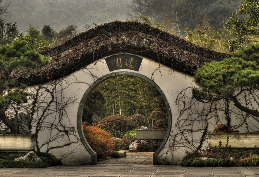 A serene garden pathway framed by a traditional circular moon gate.