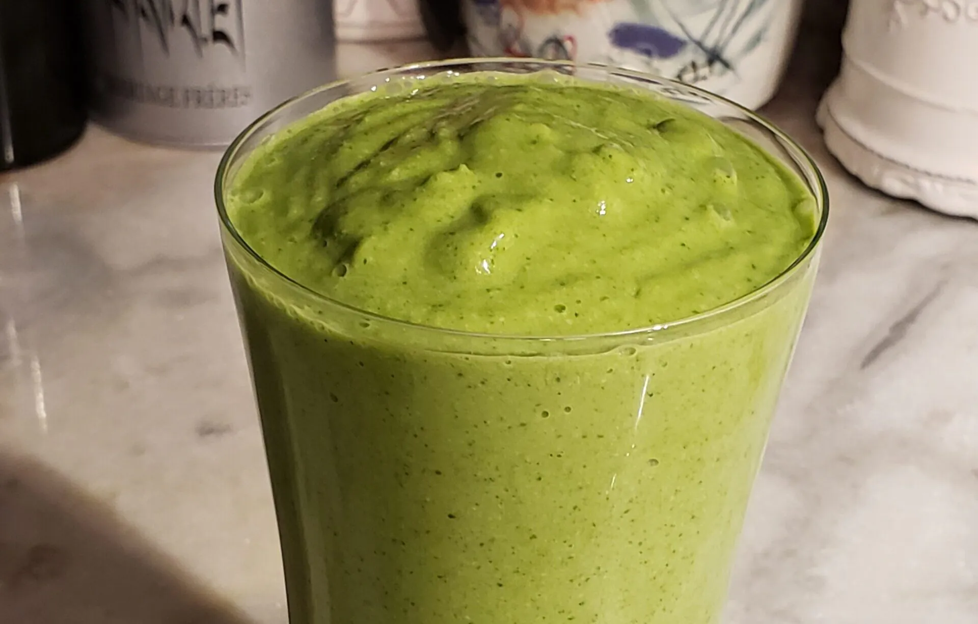 A vibrant green smoothie in a clear glass.